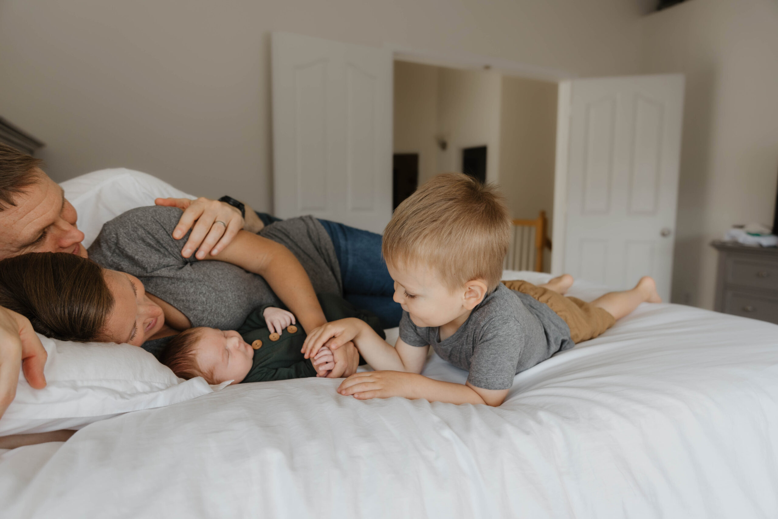 baby-led posing with family on the bed around newborn baby